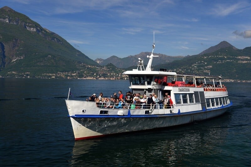 Pessoas em barco passeando pelo Lago Como