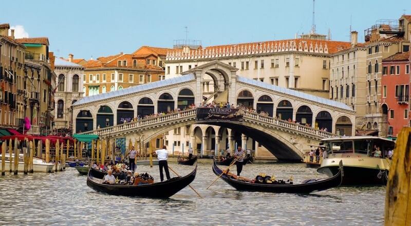 Pessoas fazendo passeio de gôndola em canal de Veneza