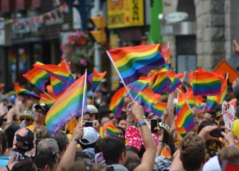 Pessoas segurando bandeirinhas de arco íris, símbolo do orgulho gay