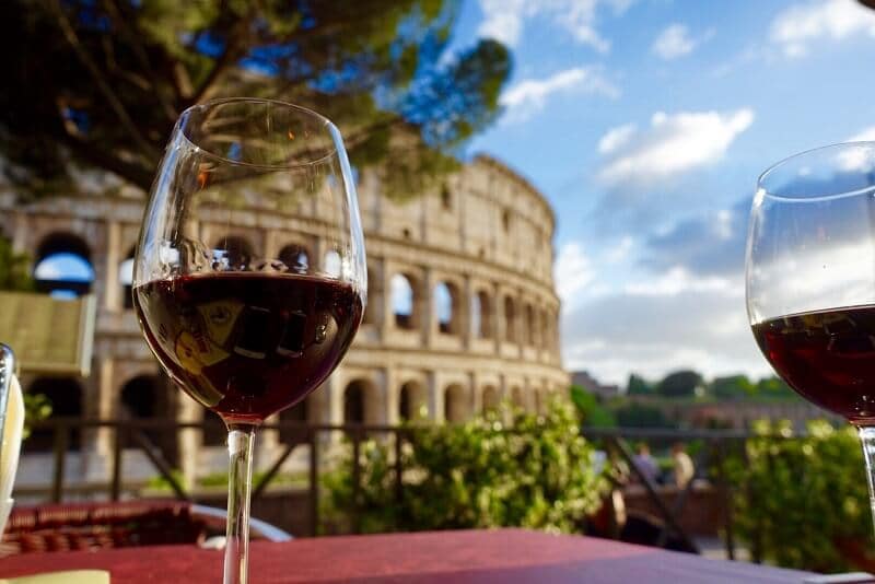 Copo de vinho e Coliseu de Roma de fundo